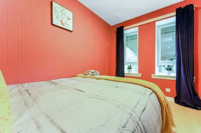 a bedroom with orange walls and a bed in it at Spacious 2-Bedroom Main Door Apartment With Private Parking in Glasgow