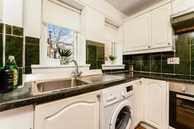 a kitchen with a sink and a dishwasher at Spacious 2-Bedroom Main Door Apartment With Private Parking in Glasgow