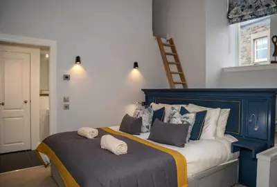 a bedroom with a blue and white bed with pillows at The Kinross Residence in Kinross