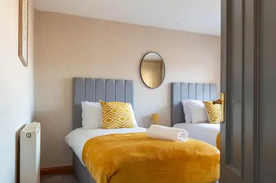a bedroom with two beds and a mirror at Gunn House in Grangemouth