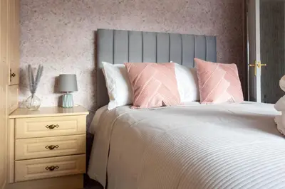 a bedroom with a bed with pink and white pillows at Gunn House in Grangemouth