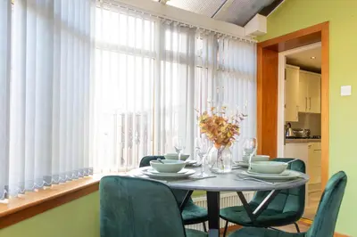 a dining room table with chairs and a large window at Gunn House in Grangemouth