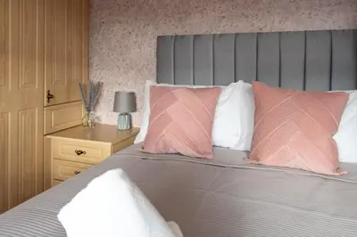 a bedroom with a bed with pink and white pillows at Gunn House in Grangemouth