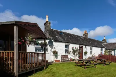 a white cottage with a picnic table in front of it at Seaview Cottage in Isle of Jura