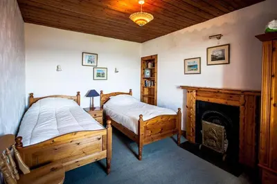 two beds in a bedroom with a fireplace at Seaview Cottage in Isle of Jura