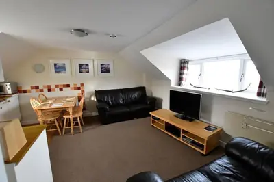 a living room with a black leather couch and a table at Argyll House Ben More in Salen