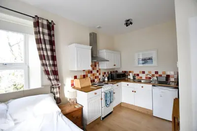 a kitchen with white cabinets and a bed in a room at Argyll House Burnside in Salen