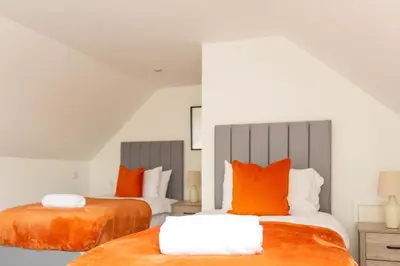two beds with orange pillows in a room at Winton House in Glasgow