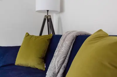 a blue couch with two yellow pillows and a lamp at Winton House in Glasgow
