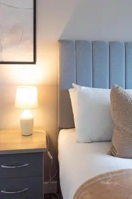 a bed with a blue headboard and a table with a lamp at Winton House in Glasgow