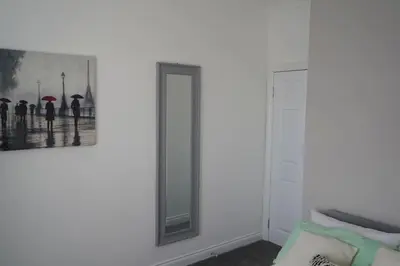 a mirror on a wall with a picture of people with umbrellas at Falkirk City Centre Stylish Two-Bedrooms Apartment in Falkirk