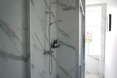 a shower in a bathroom with white marble walls at Falkirk City Centre Stylish Two-Bedrooms Apartment in Falkirk