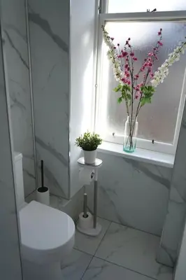 a bathroom with a toilet and flowers in a window at Falkirk City Centre Stylish Two-Bedrooms Apartment in Falkirk