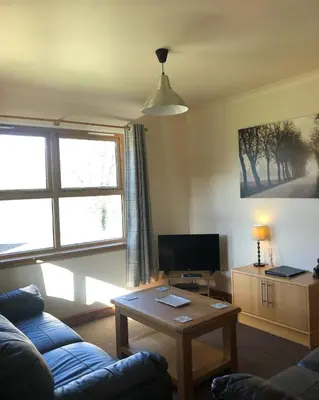 a living room with a blue couch and a table at Bracken Lodges, Loch Tay, Linnie Lodge in Aberfeldy