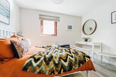 a bedroom with a bed with an orange blanket at The Merchants Gem - 2Bed & Free Parking in Glasgow