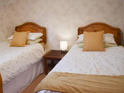 a bedroom with two beds and a table with a candle at Bayview in Kentallen