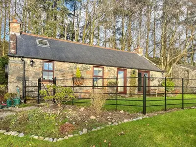 a stone house with a black fence in front of it at The Clachan Bothy in Drumpark