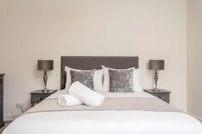 a large white bed with two lamps on either side at Cuthbert House in Prestwick