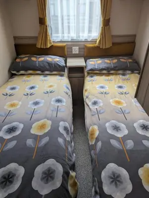 two beds in a small room with flowers on the covers at The Ardennes 66 in Dunoon