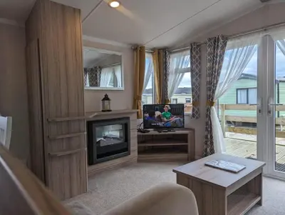 a person sitting in a living room with a tv and a fireplace at The Ardennes 66 in Dunoon