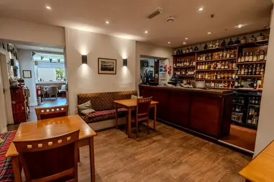 a bar in a restaurant with wooden tables and chairs at Lochranza Country Inn in Lochranza