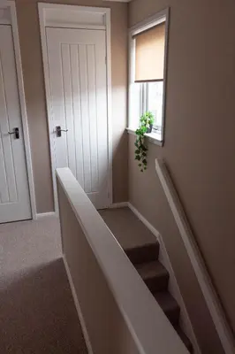 a hallway with stairs and a window and a plant at Grove House in Queensferry
