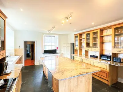 a large kitchen with wooden cabinets and a large island at Colzium Farmhouse in Blitterlees