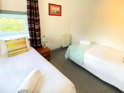 a bedroom with two beds and a window at Colzium Farmhouse in Blitterlees