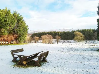 a wooden picnic table in a snow covered field at Colzium Farmhouse in Blitterlees