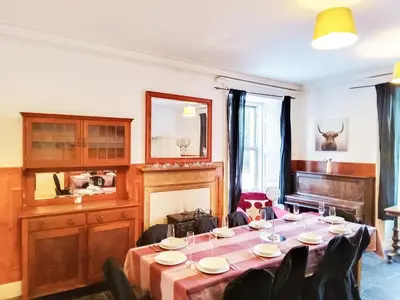 a dining room with a table and a piano at Colzium Farmhouse in Blitterlees
