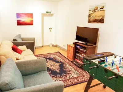 a living room with a couch and a table with a tv at Colzium Farmhouse in Blitterlees