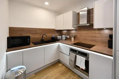 a kitchen with white cabinets and a sink and a microwave at Troon Portland Apt B in Troon