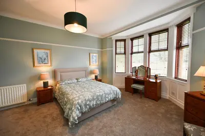 a bedroom with a bed and a desk and windows at Dunvegan Apartment Troon in Troon