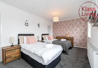 two beds in a bedroom with pink wallpaper at Aitkenhead house by Klass Living in Coatbridge