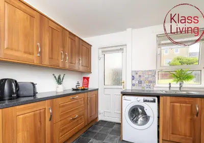 a kitchen with wooden cabinets and a washing machine at Aitkenhead house by Klass Living in Coatbridge