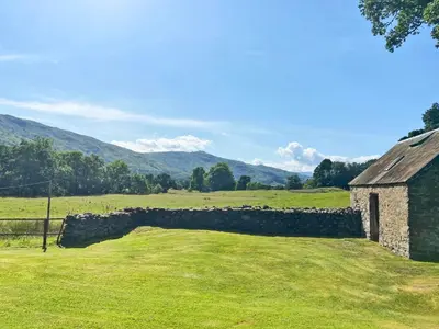 an old stone building in a field with a stone wall at Bridge Park in Killin