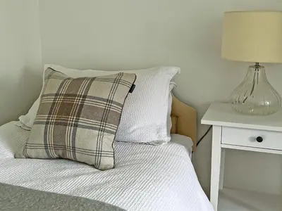 a bed with a pillow and a lamp on a table at Bridge Park in Killin