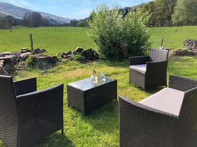 a patio with chairs and a table in a field at Bridge Park in Killin