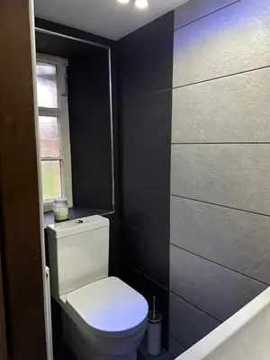 a bathroom with a toilet and a black wall at The Inverleither in Edinburgh