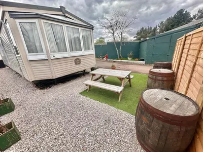 a picnic table and two barrels and a caravan at Atlas 2 Bedroom Caravan - Located in Uddingston, Glasgow at Maryville Caravan Site in Uddingston