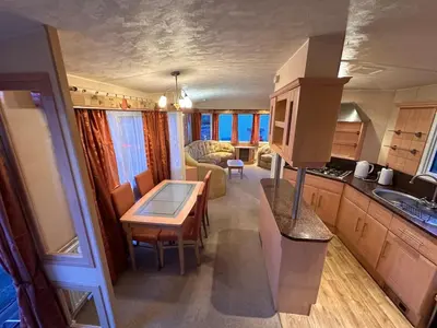 a kitchen and a living room with a table in a house at Atlas 2 Bedroom Caravan - Located in Uddingston, Glasgow at Maryville Caravan Site in Uddingston