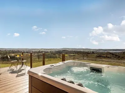 a hot tub on a deck with a view at Oakwood Lodge in Lochwinnoch