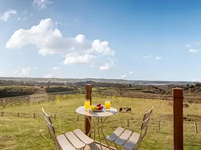 a table with chairs and a plate of food on a field at Oakwood Lodge in Lochwinnoch