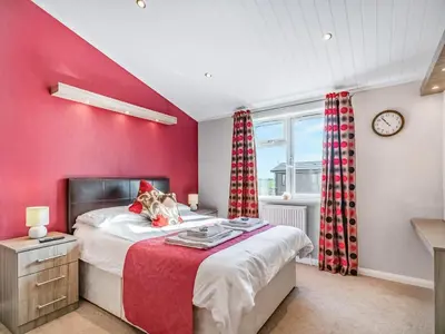 a bedroom with a red wall with a bed and a clock at Oakwood Lodge in Lochwinnoch