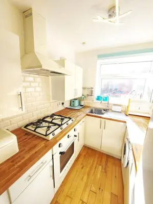 a kitchen with white cabinets and a stove top oven at The Relish - ground floor flat in Largs in Largs