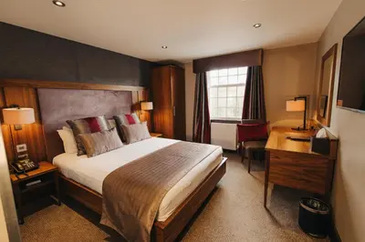 a hotel room with a large bed and a desk at Busby Hotel in Busby