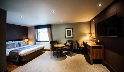 a hotel room with a bed and a table and chairs at Busby Hotel in Busby