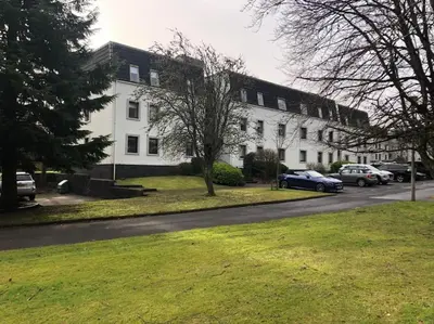 a white house with cars parked in front of it at Gleneagles Apartment in Auchterarder
