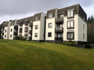 an apartment building with a green field in front of it at Gleneagles Apartment in Auchterarder