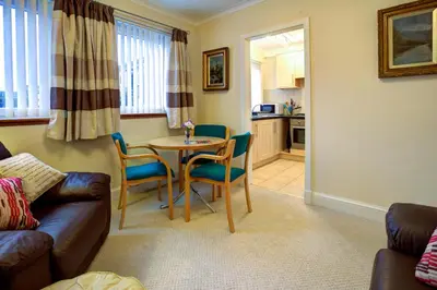 a living room with a table and chairs and a kitchen at Cedars Apartment in Kirn
